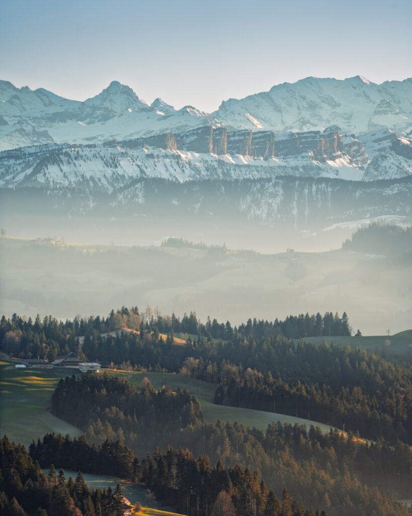 Hügel und Wälder im Dunst vor der Alpenkette